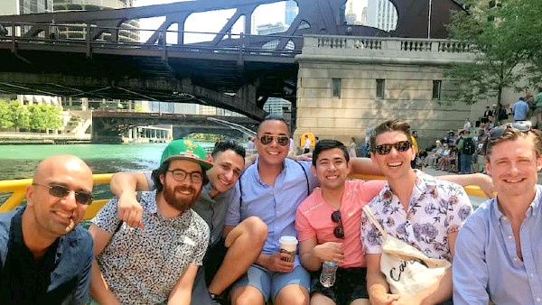 Group photo on a boat with river and bridges in the background
