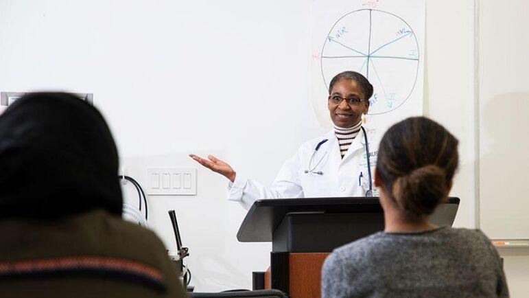 A professor at a podium addresses a classroom