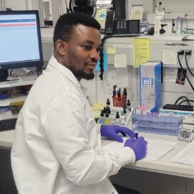 Student wearing white coat seated at a lab bench