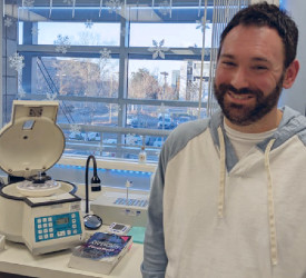 Student in front of a lab bench smiling at the camera