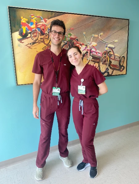 Two residents in matching burgundy scrubs