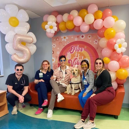 A group of residents seated with a dog under a balloon arch