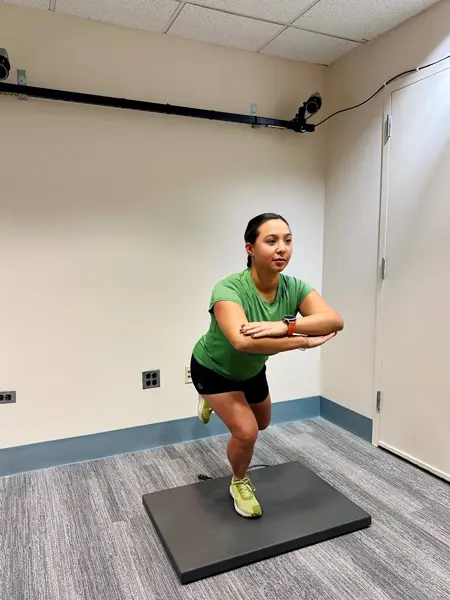 A person on a force plate in single leg squat position in the MARS Lab