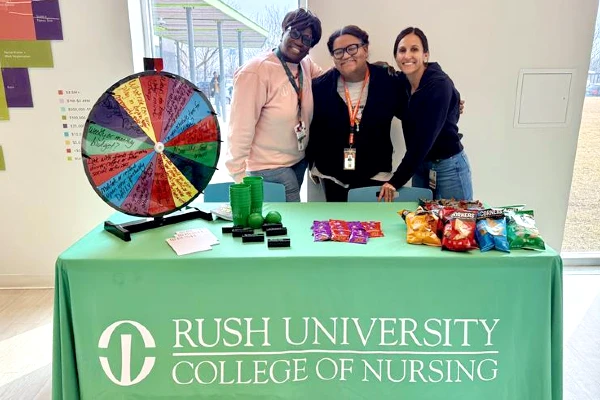 Three staff members stand behind a promotional table at an event