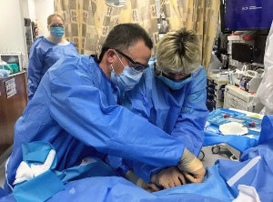 Two surgical professionals perform a procedure