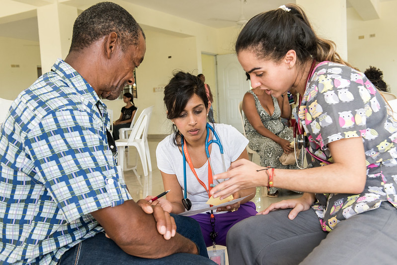 Two health care providers lean forward to consult a patient's chart