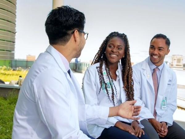 Three medical students seated in a rooftop garden, smiling and talking