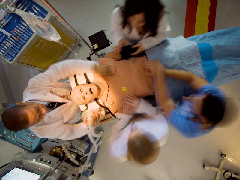 A group of clinicians perform a procedure on a manikin