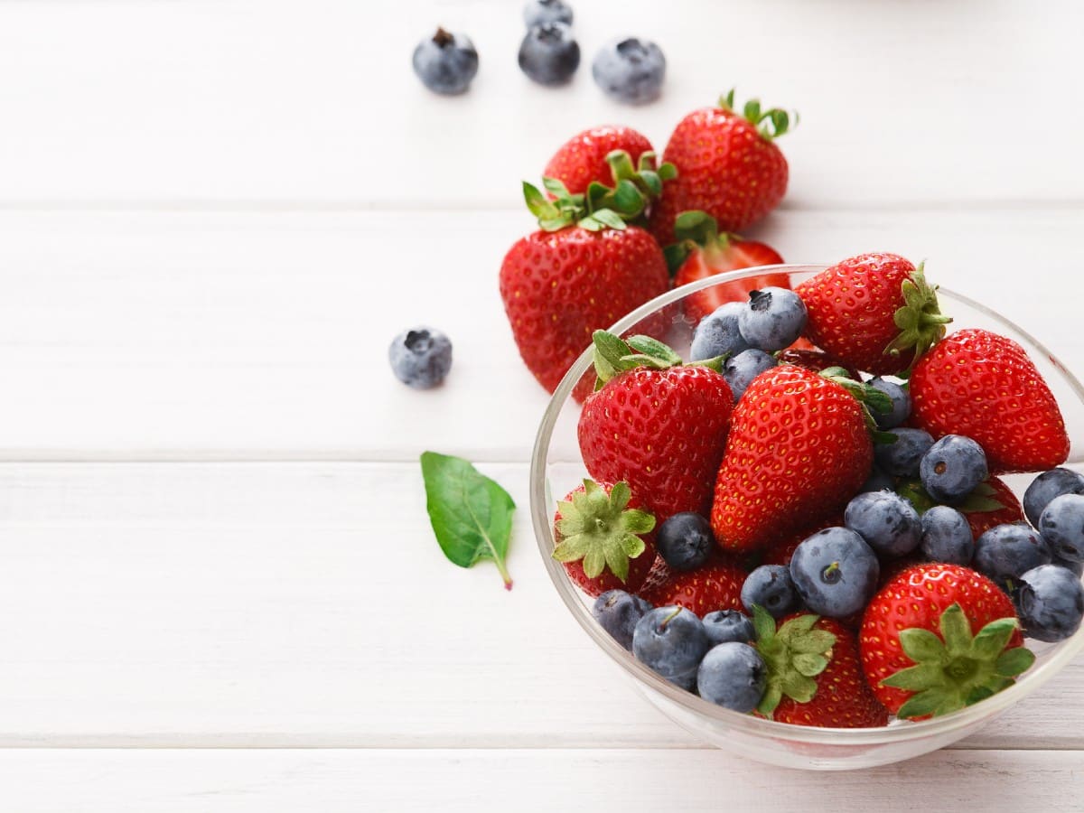 A mix of blueberries and strawberries in a glass bowl