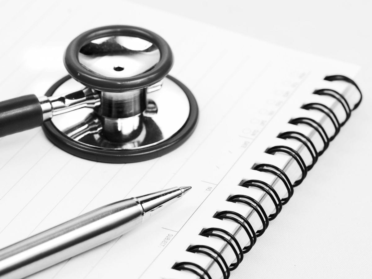 Stethoscope and pen resting on an open notepad