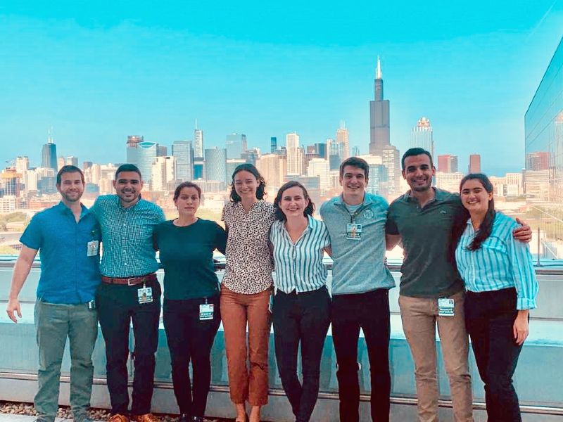 A group of smiling people on a rooftop with the Chicago skyline in the distance