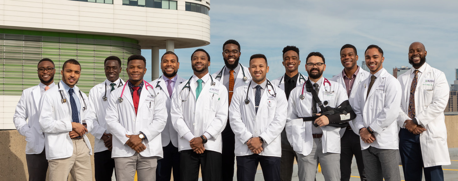 Diverse group of physicians in white coats standing outside with the Rush Tower building behind them