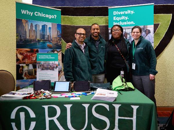 Four people tabling at an event with Rush banners and materials
