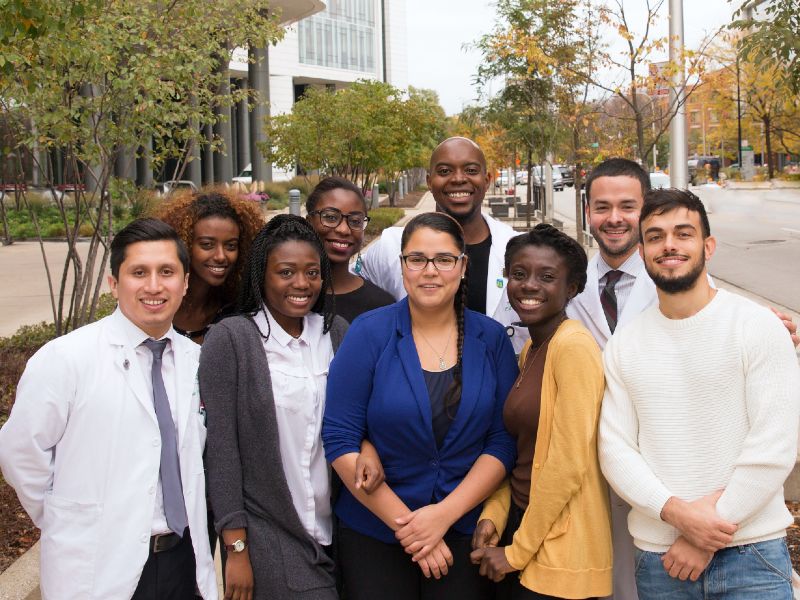 A group of diverse medical students stands together outside for a photo