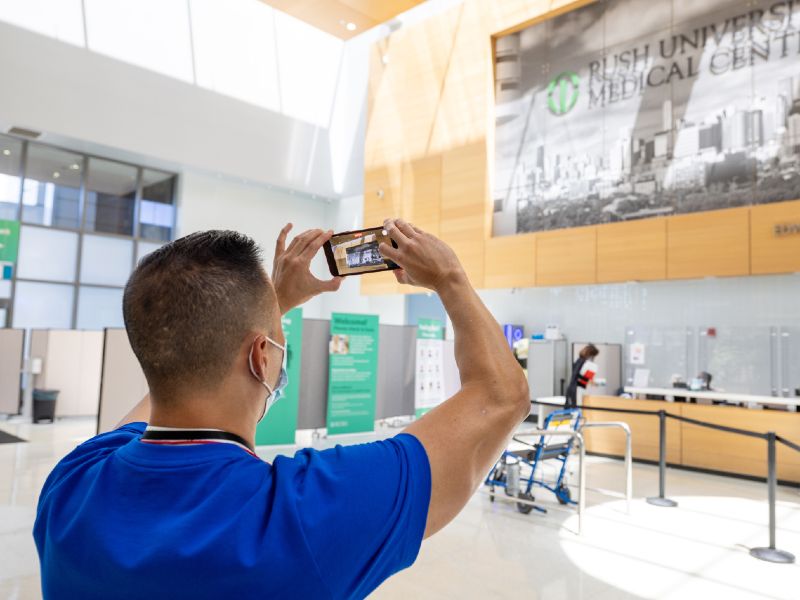 A tour participant holds up his phone to take a photo of a large sign in the Atrium