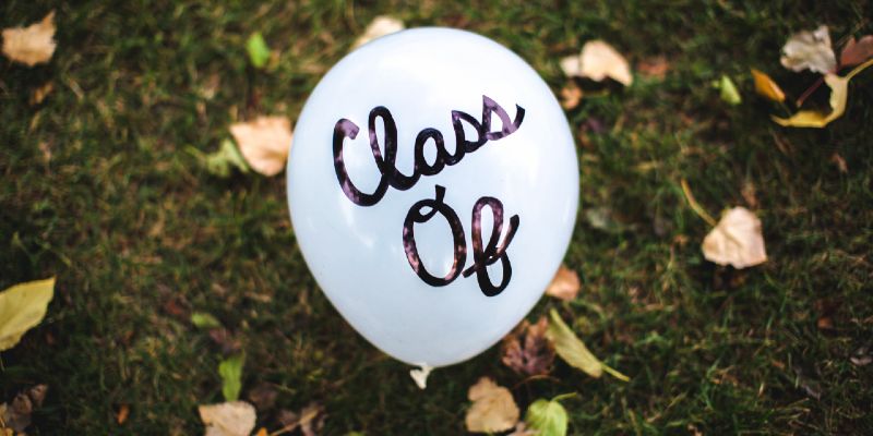 A balloon printed with Class Of resting on a grassy lawn