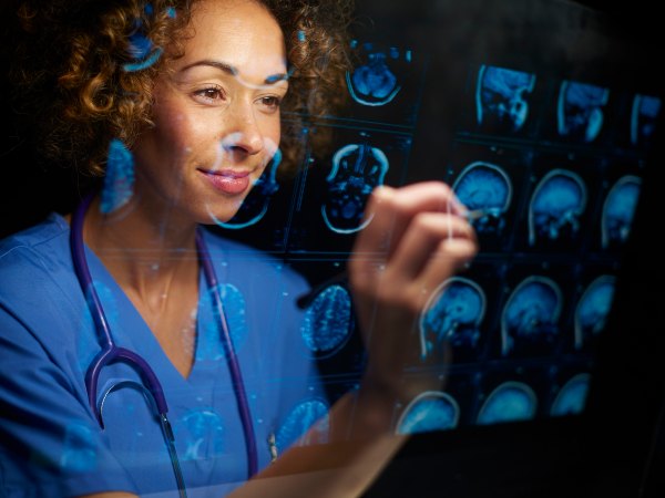 A health professional wearing scrubs examines digital images of brains