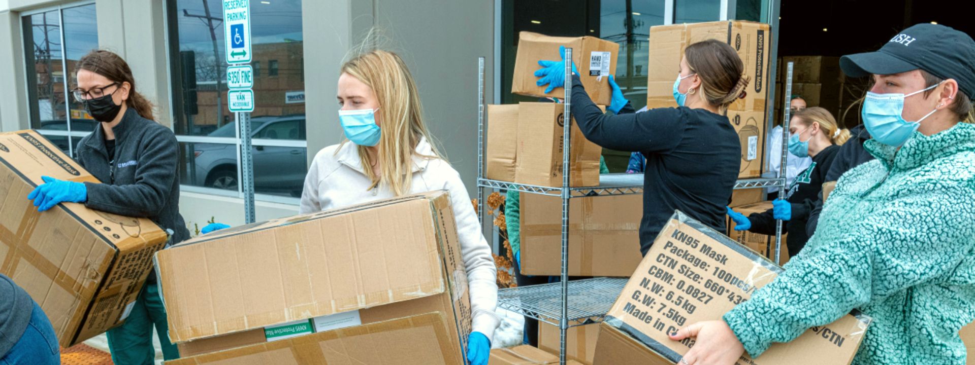 Students load boxes of KN95 masks into cars for donation