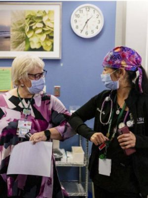 Two nurses bump elbows in greeting