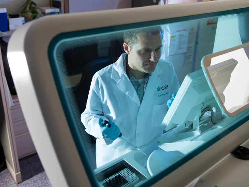 Researcher wearing a white coat seated in a lab