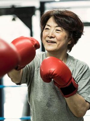 A woman wearing boxing gloves spars in a ring