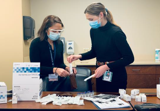 Two women wearing surgical masks pack supplies 