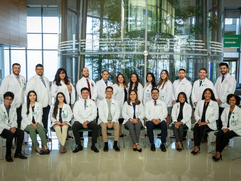 Members of the Latinx Medical Student Association pose together wearing white coats
