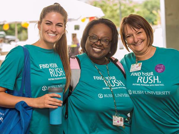 Three people wearing Rush T-shirts smiling outdoors