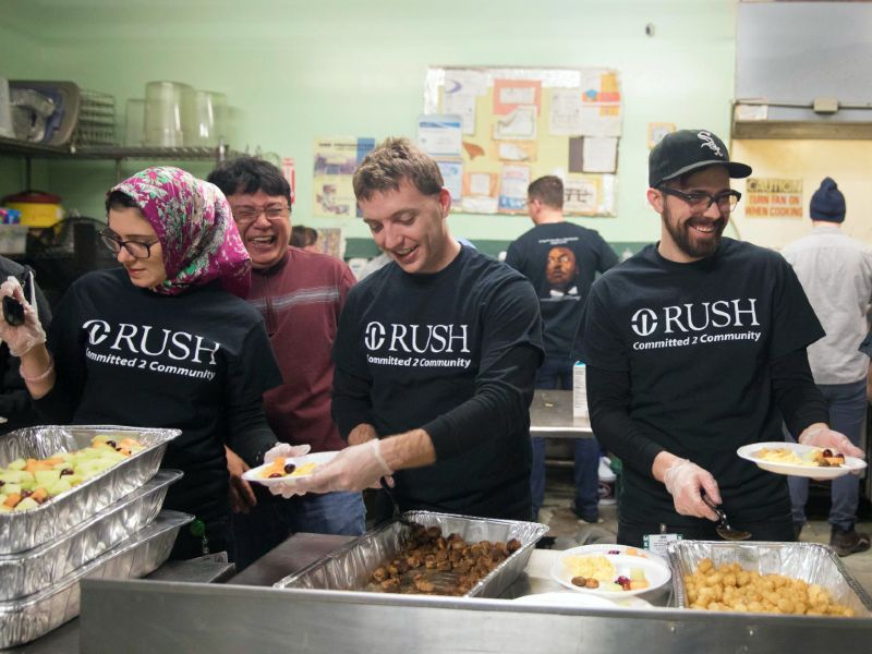 Students wearing Rush t-shirts serve breakfast on a buffet line