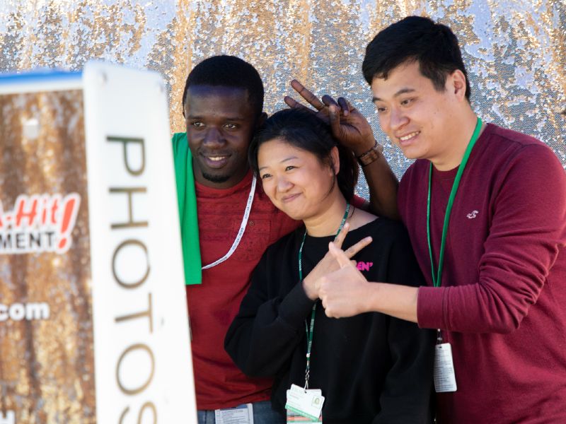 Three students pose at an outdoor photo booth