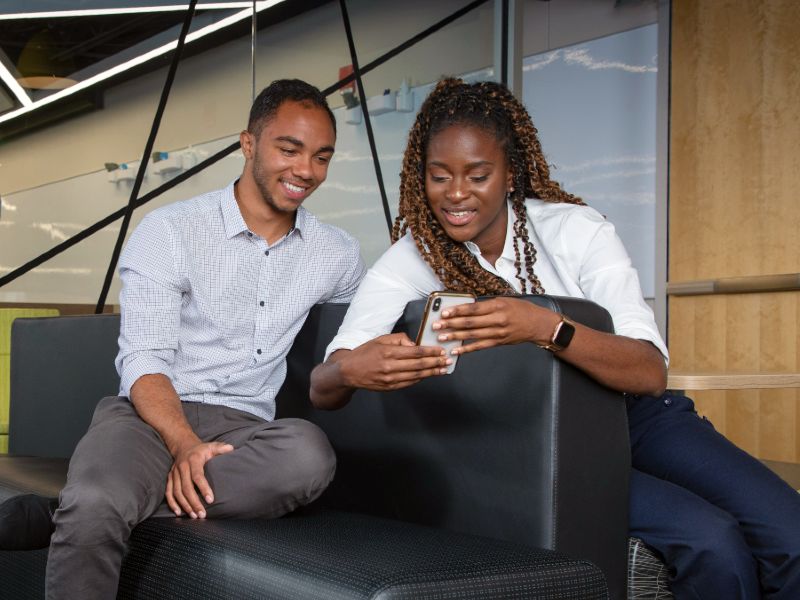 Two students seated in a lounge looking at a phone screen