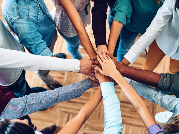 A group of diverse people standing in a circle with hands in the middle