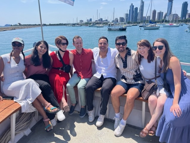 The PGY-1 residents sit on the front of a boat on Lake Michigan with the Chicago skyline behind them.