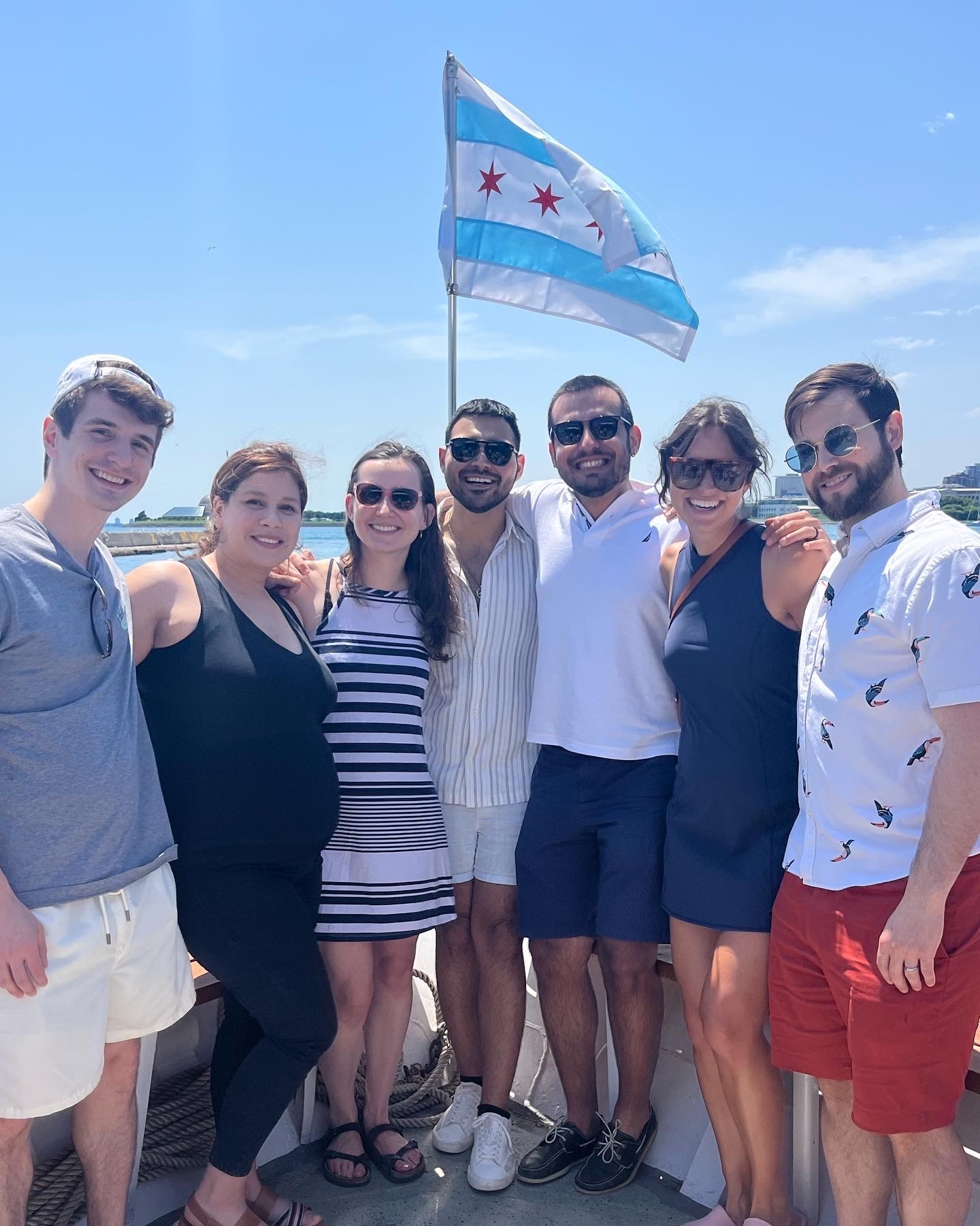 The PGY-2 residents stand on the front of a boat on Lake Michigan with a Chicago flag above them.