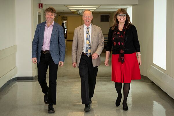 Three people walking down a corridor