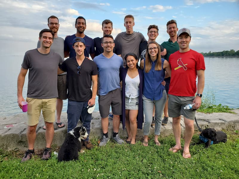 The emergency medicine residents of 2022 stand together in casual clothing in front of a lake.