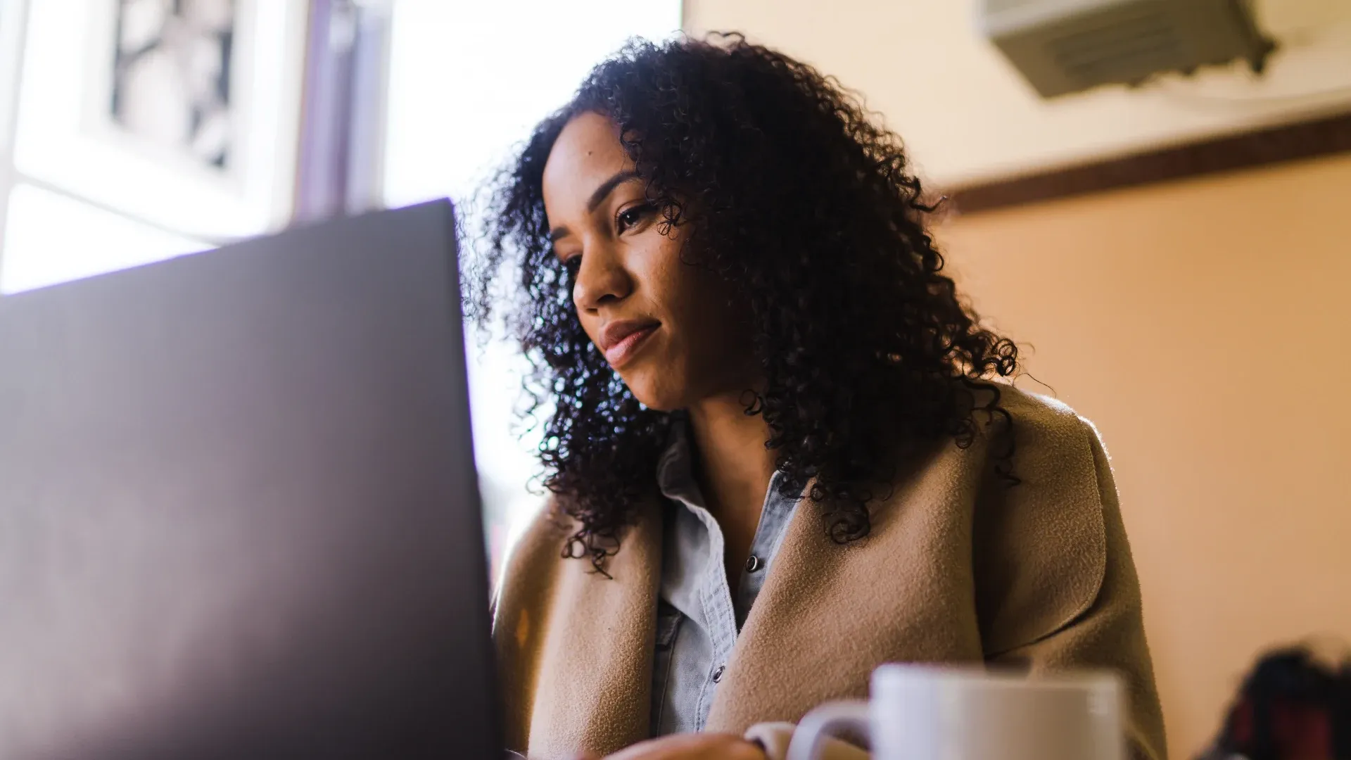 A Black woman looking at her laptop.