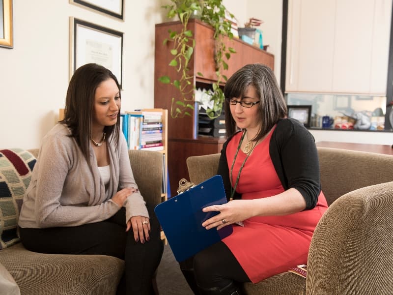Two woman look over information on a clipboard.