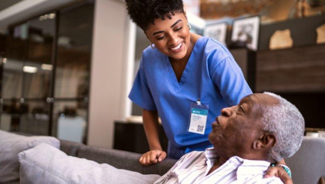 A physician comforts a senior man seated on a couch.