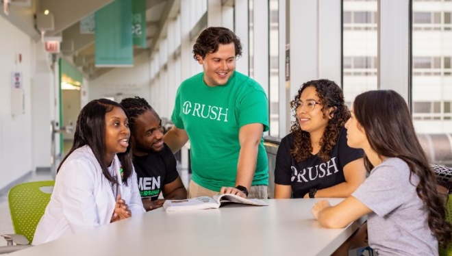 A group of students in conversation with an open textbook on the table in front of them