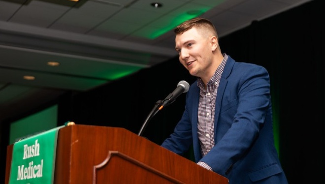 A speaker stands at a podium speaking into a microphone