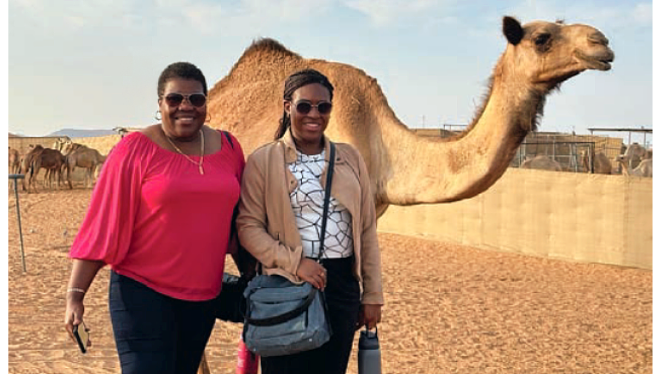 Two women take a selfie in front of a camera