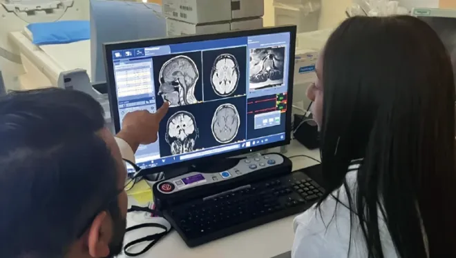Two health care practitioners review MRI images on a computer monitor
