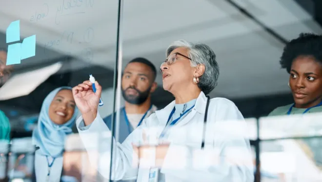 A group of health care providers in conference making notes on an erasable board