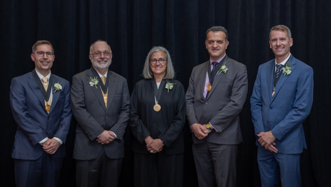 Five faculty members wearing medals stand together