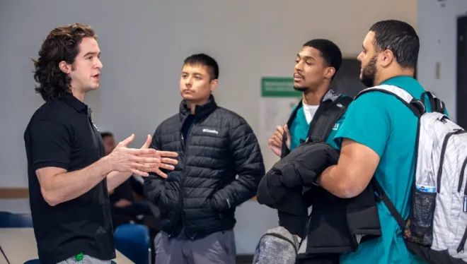 A student gestures with his hands while speaking the three men wearing scrubs