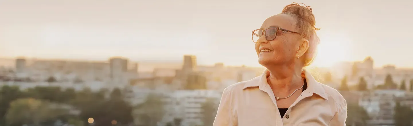 A person facing the camera looking at the sky with a skyline behind