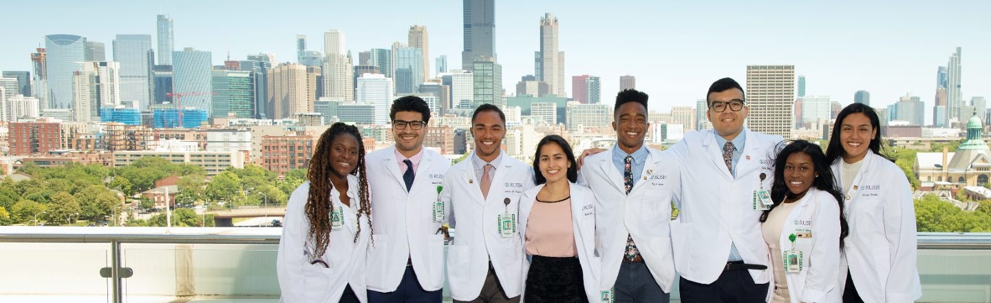 A group of students wearing white coats ona rooftop with the Chicago skyline visible in the distance