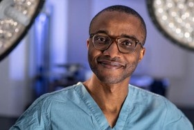 Surgeon wearing scrubs and smiling to camera