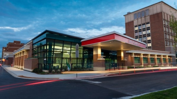 Exterior of RUSH Oak Park's emergency room entrance. It is almost evening as the exterior lights turn on and the cloudy blue sky grows dark.